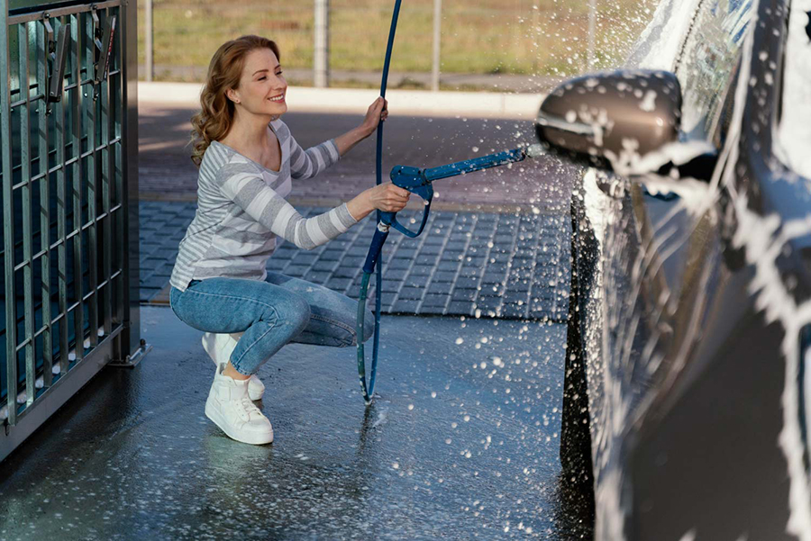 Mujer lavando el coche a mano en estación de servicio de Carburantes Blue Puertollano